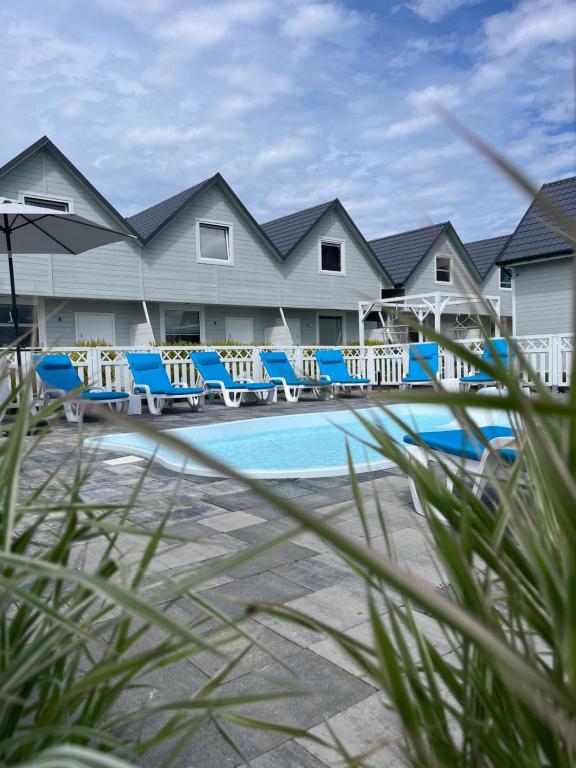 un complexe avec des chaises bleues et une piscine dans l'établissement Holiday House Sarbinowo, à Sarbinowo