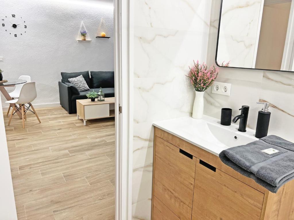 a bathroom with a sink and a living room at Coqueto con PISCINA, nuevo a 50m del mar, Parking Gratis in El Campello