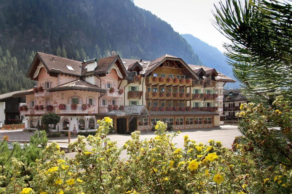 a large building in front of a mountain at Hotel Soreghes Gran Chalet in Campitello di Fassa