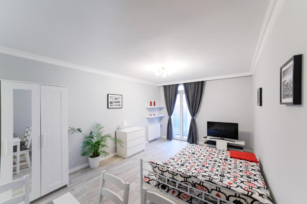 Habitación blanca con cama y TV en Apartament Grójecka Korotyńskiego en Varsovia