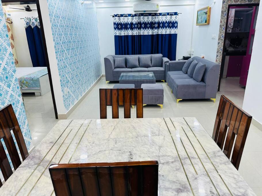 Una sala de estar con una mesa y sillas y un sofá. en Kartik, en Varanasi