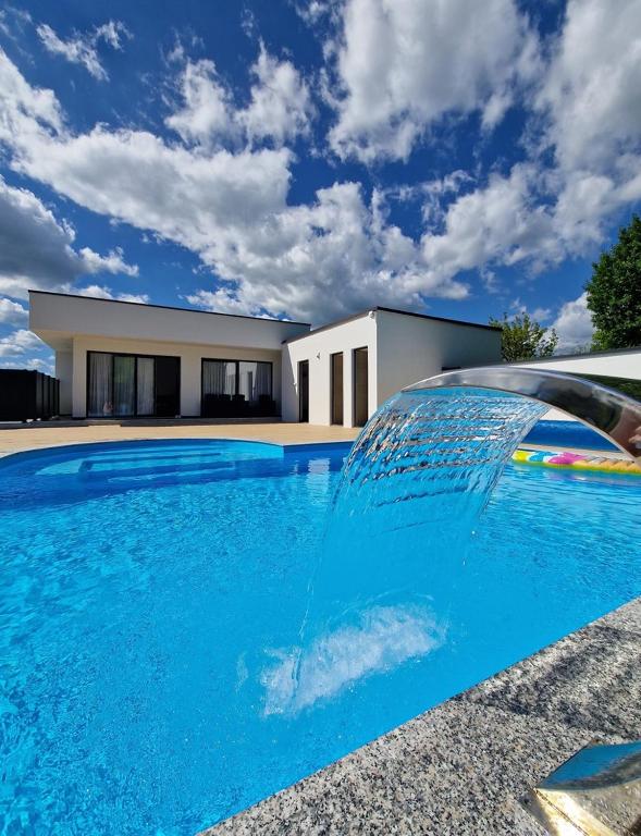 a swimming pool with a fountain in front of a house at Villa AS in Bihać