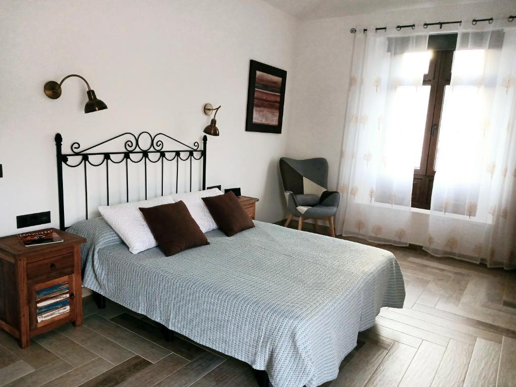 Un dormitorio con una cama y una silla y una ventana. en Casa del Valle 10, en Yaiza