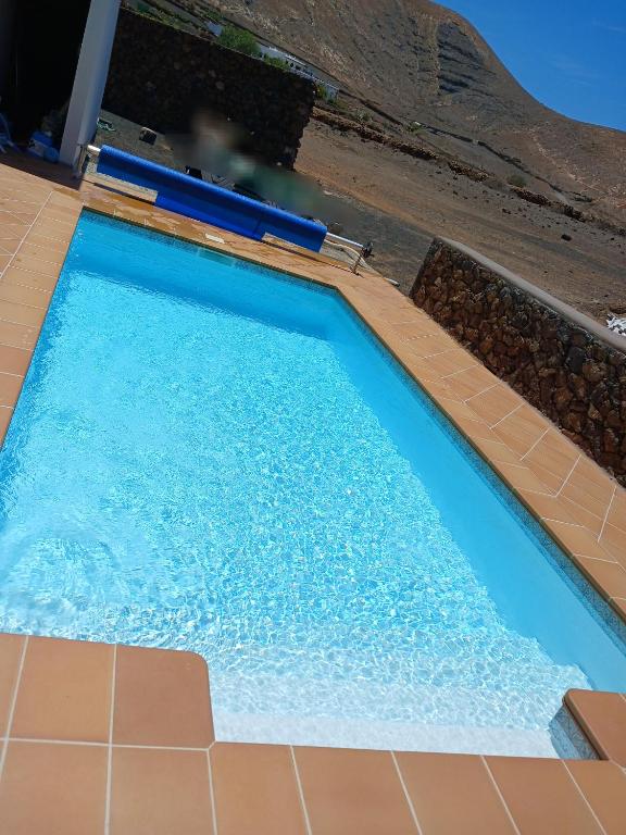 a swimming pool with blue water on a tile floor at Casa del Valle 10 in Yaiza