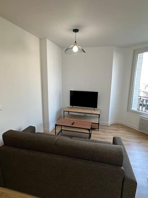 un salon avec un canapé et une télévision à écran plat dans l'établissement Appartement Moderne, à Gennevilliers