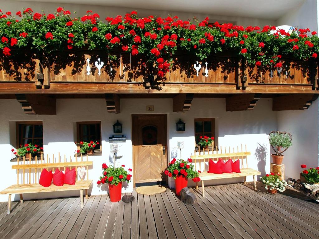 Ein Gebäude mit einem Haufen roter Blumen drauf. in der Unterkunft Alpenferienwohnung Strickner in Neustift im Stubaital