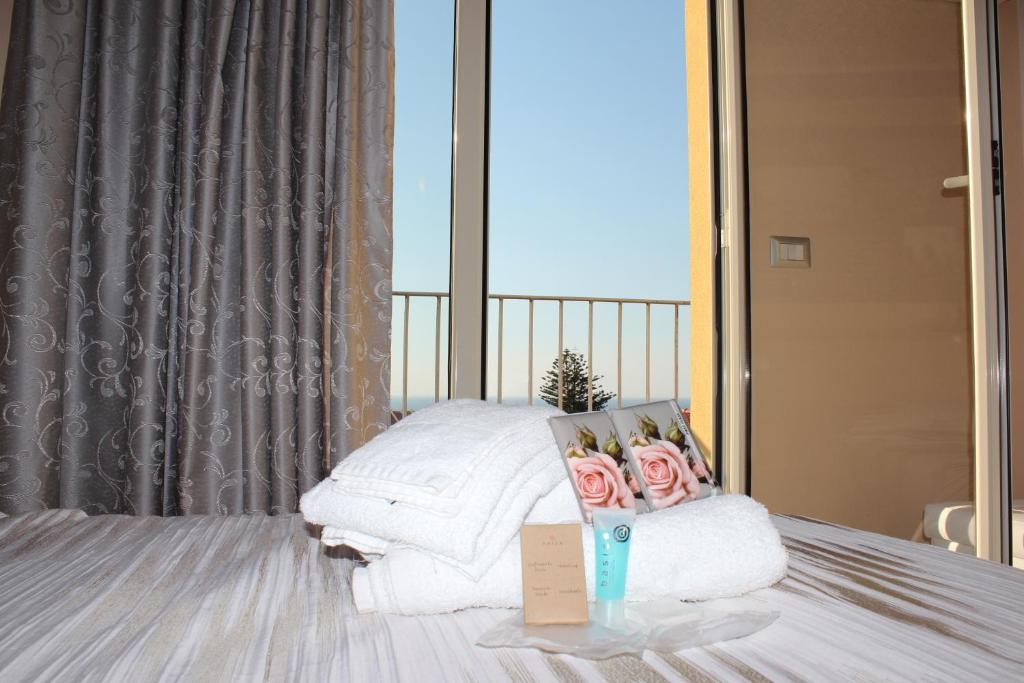 シッラにあるB&B Al Vicolettoのベッド(白いタオル、ピンクのバラ付)