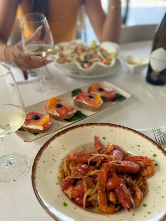 a plate of food on a table with wine glasses at HOTEL BAR RESTORANT YLLI in Shëngjin