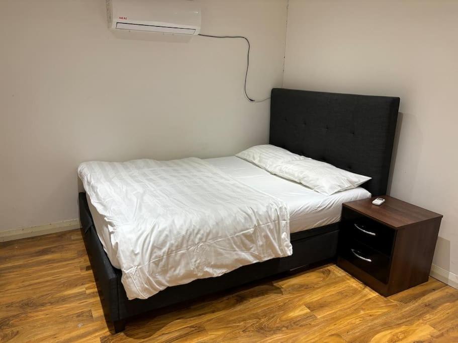 a bed with a black headboard and a night stand at One bed Flat in Perivale