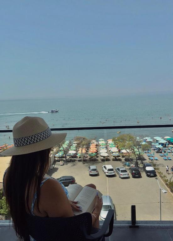 a woman sitting in a chair reading a book near the beach at HOTEL BAR RESTORANT YLLI in Shëngjin