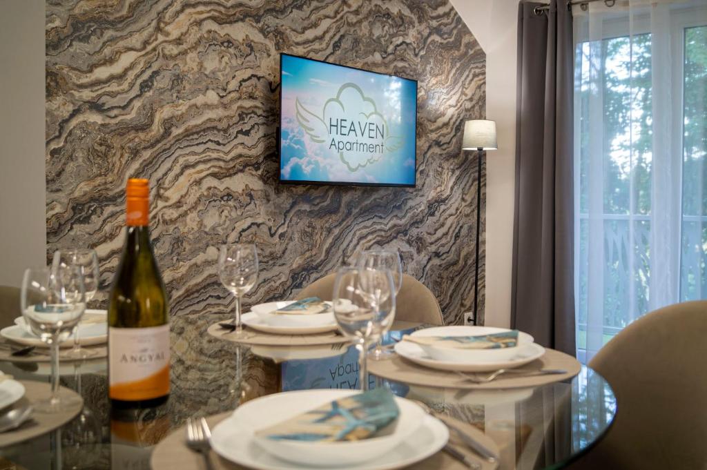 a table with a bottle of wine and glasses at Heaven Apartment in Hajdúszoboszló