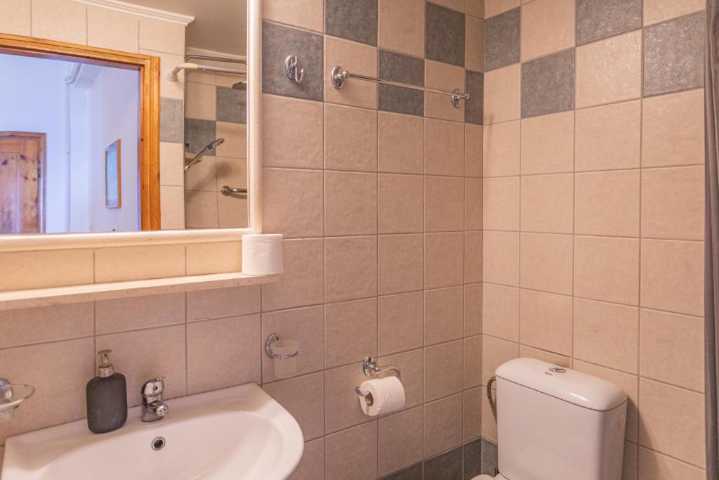 a bathroom with a toilet and a sink and a mirror at Dimitra's Studios in Stoupa