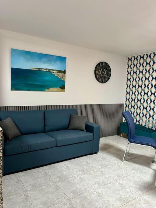 un soggiorno con divano blu e orologio di Iris Chic Residence a Marsaskala