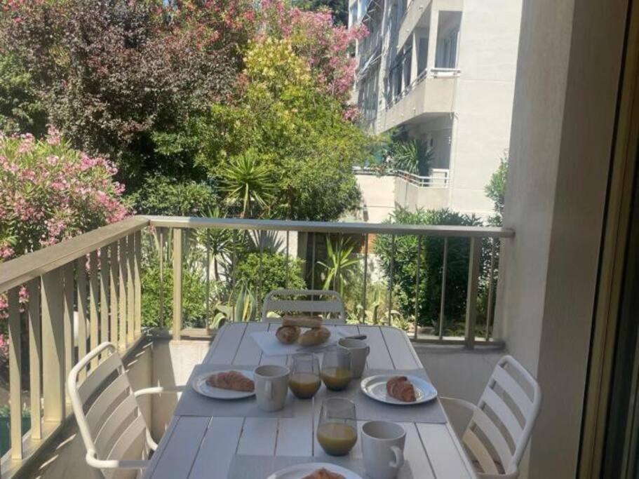 une table blanche avec des assiettes de nourriture sur un balcon dans l'établissement Studio AC with Balcony by Olidesi, à Cannes