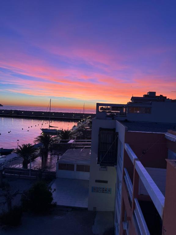 un coucher de soleil sur une étendue d'eau avec un bâtiment dans l'établissement L'Albatros, à Marseille