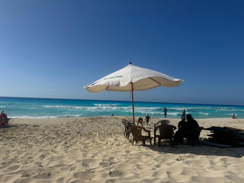 a group of people sitting under an umbrella on the beach at Grand hills in El Hamam