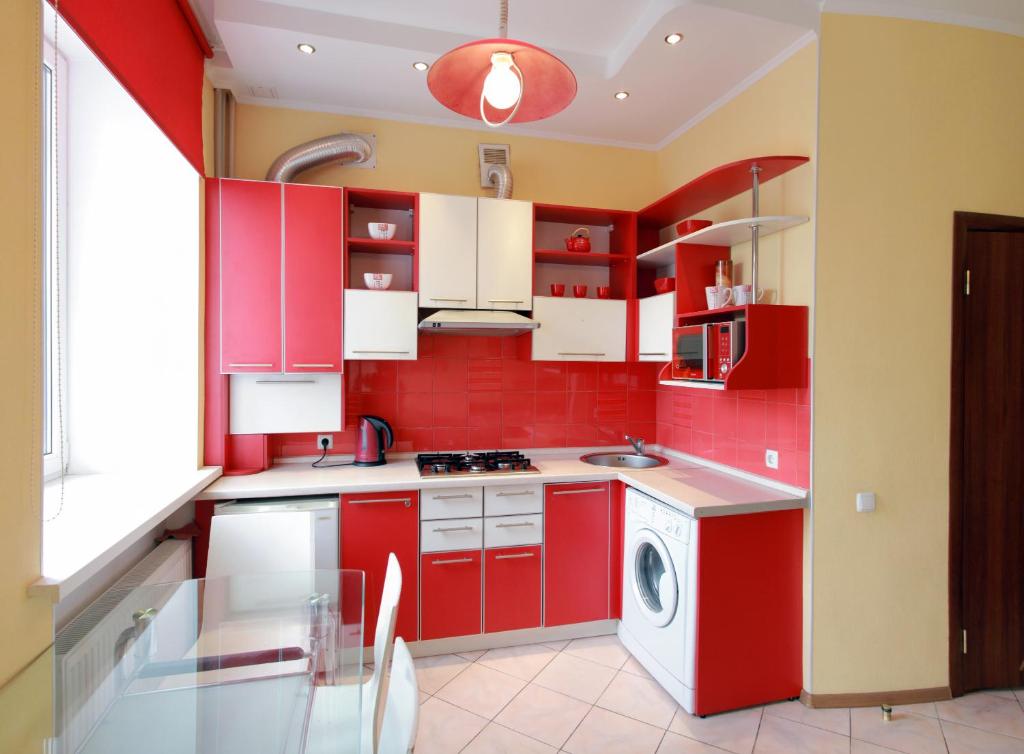 a red kitchen with white cabinets and a washing machine at VIP studio in CENTER!!! in Mykolaiv