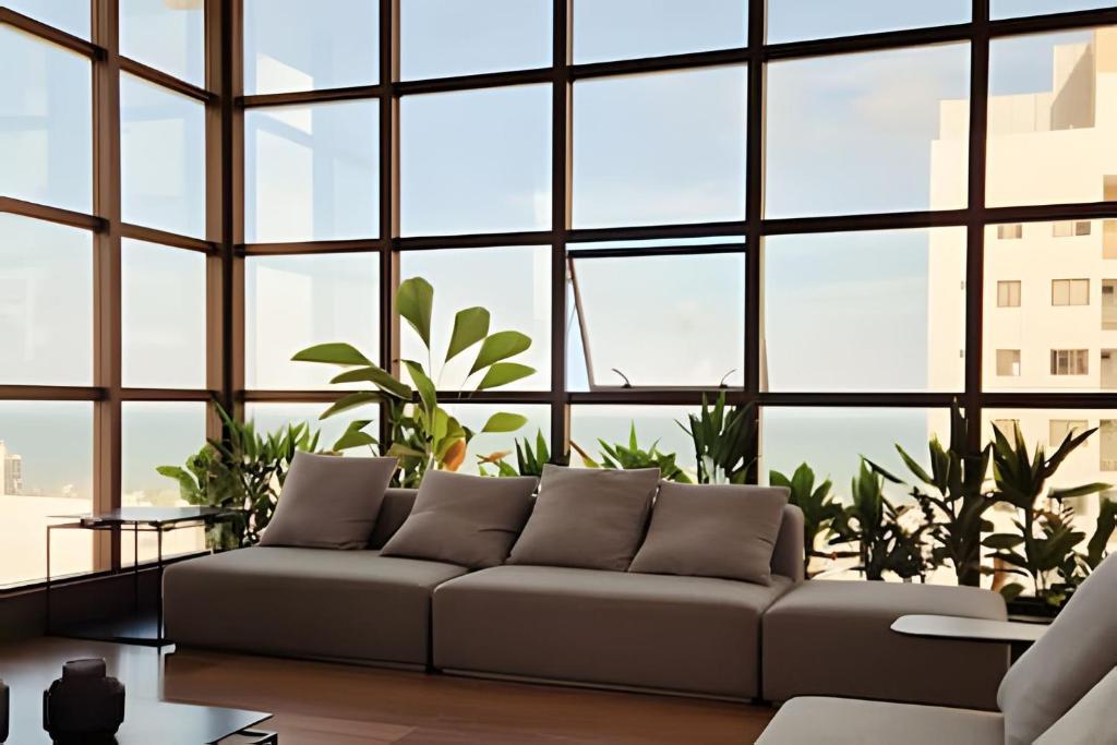a living room with a couch and large windows at Apto no Co House com vista maravilhosa de Tambaú in João Pessoa