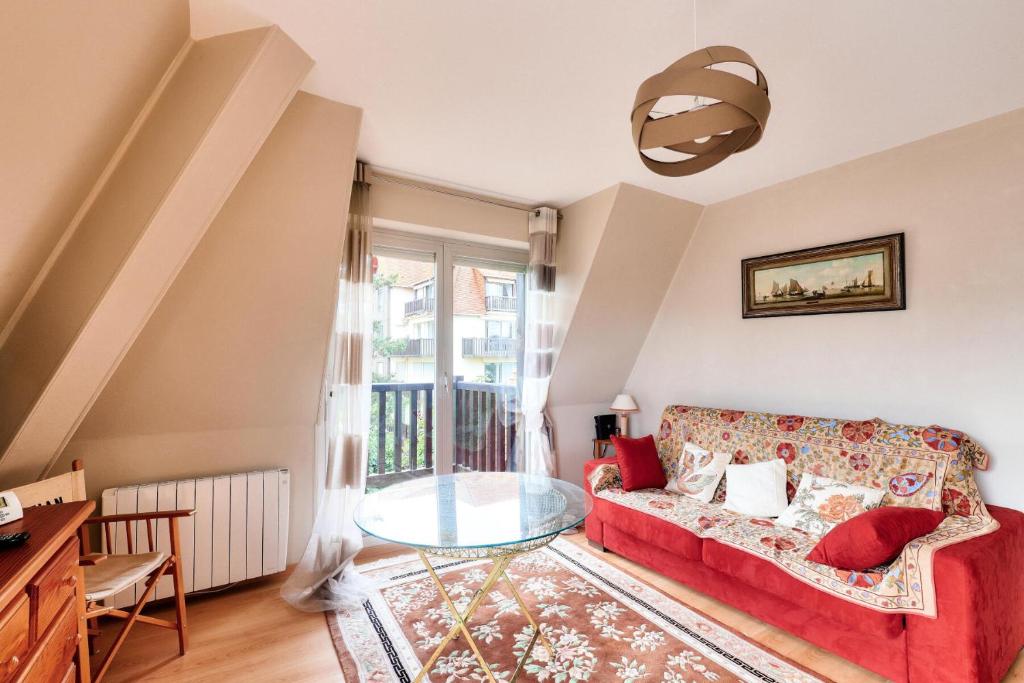 un salon avec un canapé rouge et une table en verre dans l'établissement Résidence Le Sévigné - maeva Home - Appartement 2 pièces 4 personnes - Sélection MAE-3231, à Deauville