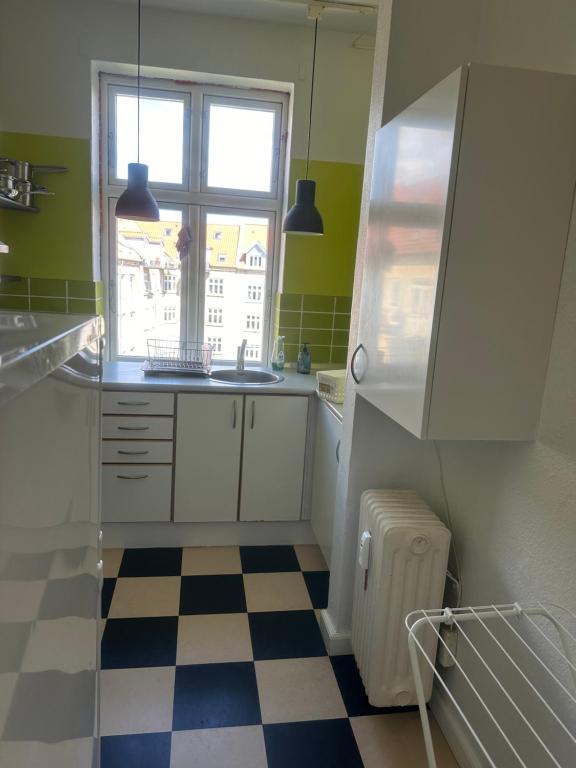 a kitchen with a sink and a window and a checkered floor at Cozy Corner in Aalborg