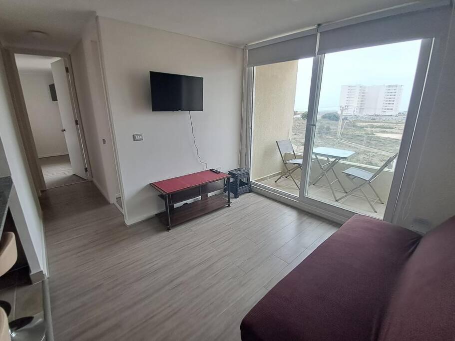 Habitación con cama, mesa y balcón. en Apartamento a pasos del Mar, en La Serena