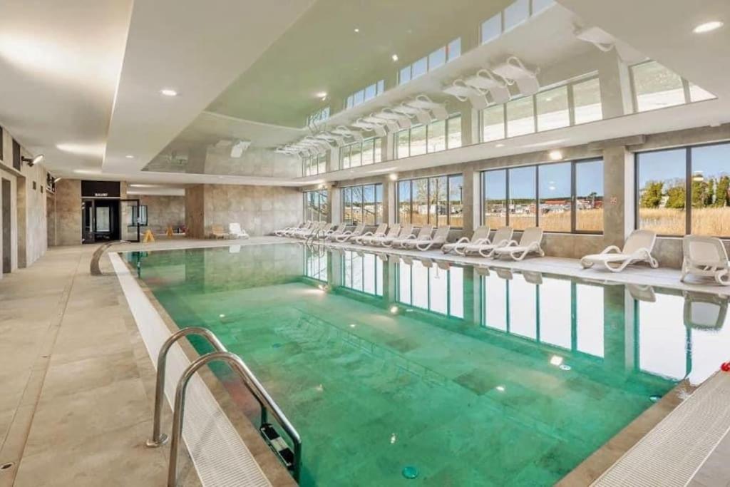 a large swimming pool with green water in a building at STAR Apartament & Spa Dziwnów in Dziwnów