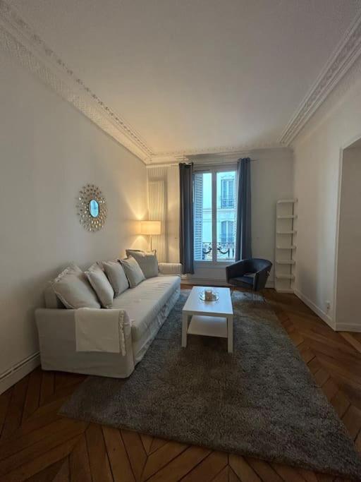 un salon avec un canapé blanc et une table dans l'établissement 3 pièces dans le coeur du 16e, à Paris