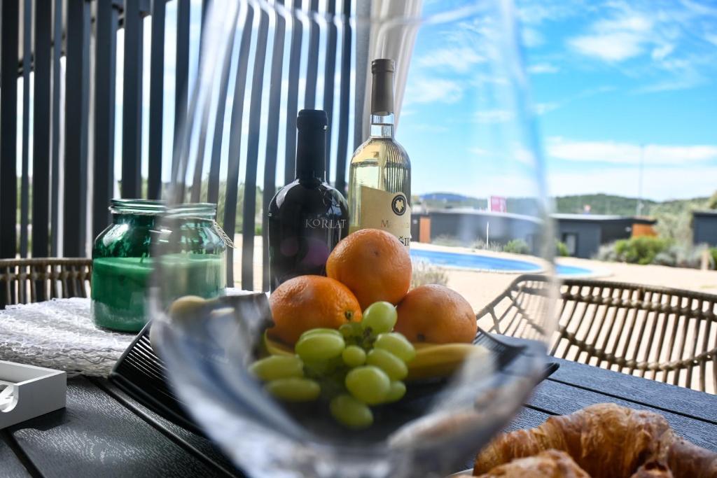 a plate of fruit on a table with wine bottles at Ausblick Sunce i More Mobilehome in Pirovac