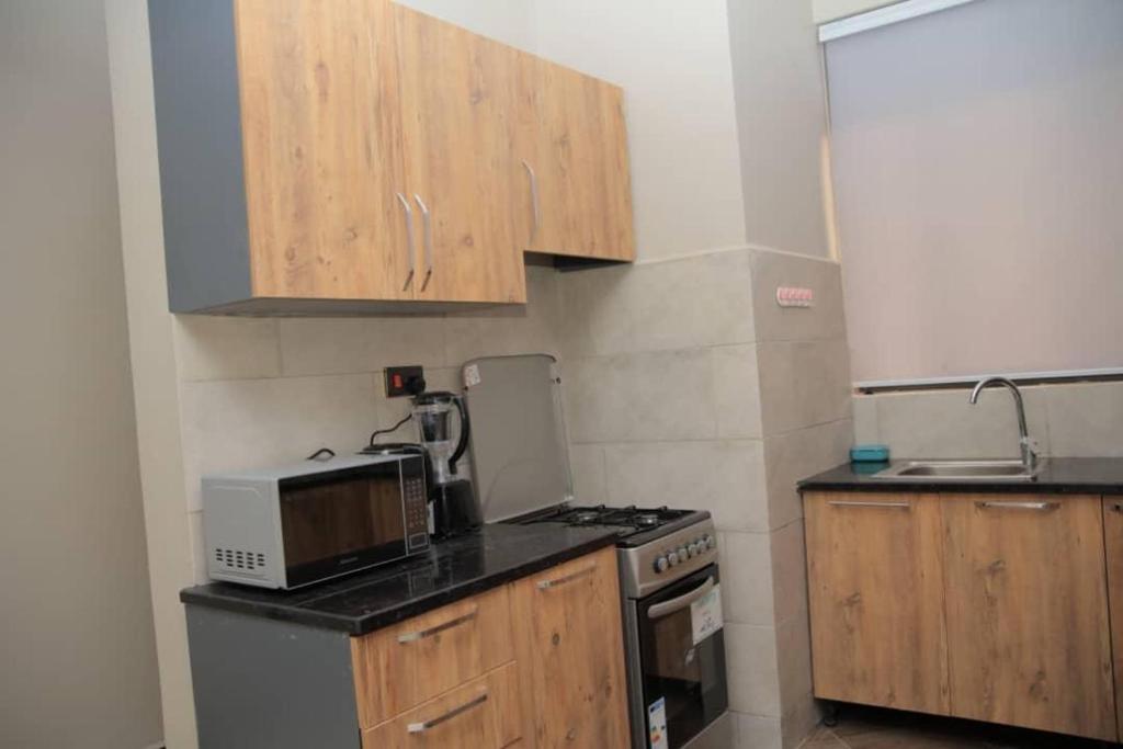 a kitchen with a microwave and a stove top oven at Cozy Condo Najjera in Kampala