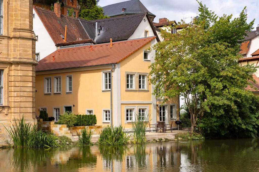 ein gelbes Haus neben einem Gewässer in der Unterkunft Concordia33 - Traumferienwohnung an der Regnitz in Bamberg