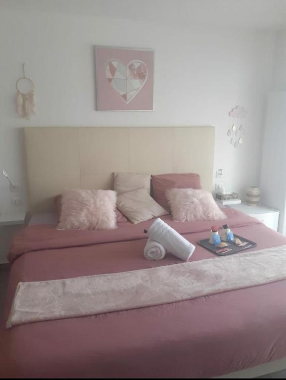 - un grand lit rose avec des draps et des oreillers roses dans l'établissement Love Room Séduction, à Tremblay-en-France