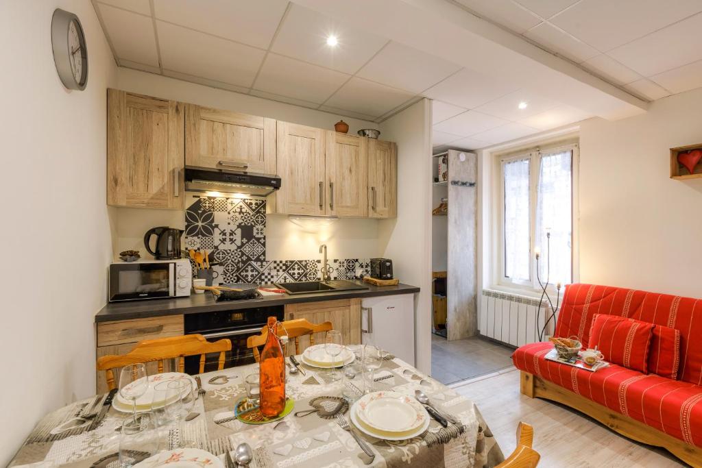 Il comprend une cuisine et un salon avec une table et un canapé rouge. dans l'établissement La Maisonnée de Julie - Happy Rentals, à Chamonix-Mont-Blanc