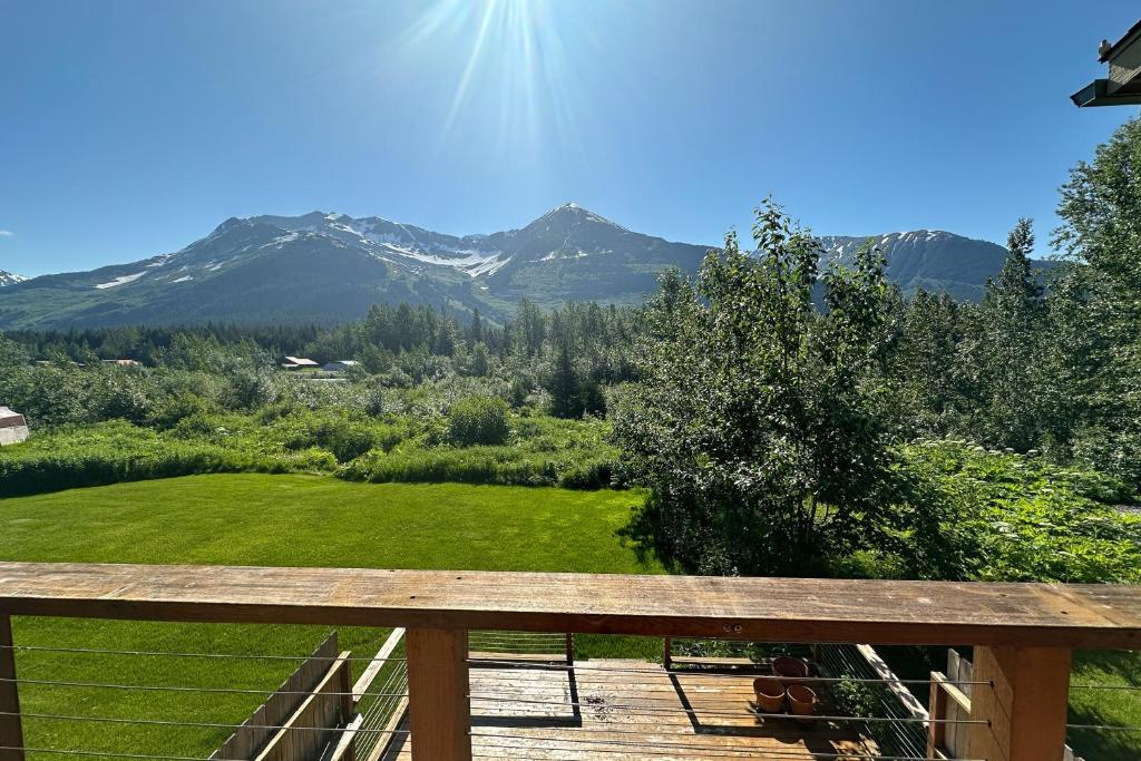 un banco de madera en una terraza con montañas al fondo en Enchanted Evergreen Escape, en Girdwood