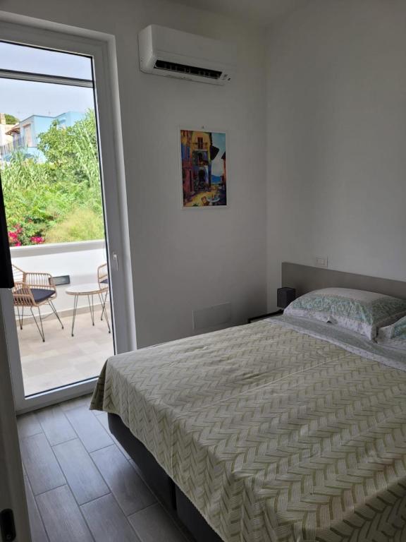 a bedroom with a bed and a sliding glass door at Cozy Corner Apartment Forio in Forio d'Ischia