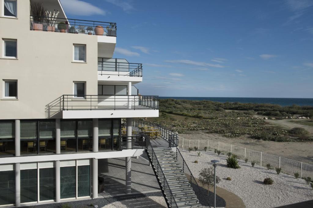 a building with a staircase leading to the ocean at Domitys Les Dunes D'argent in Saint-Cyprien