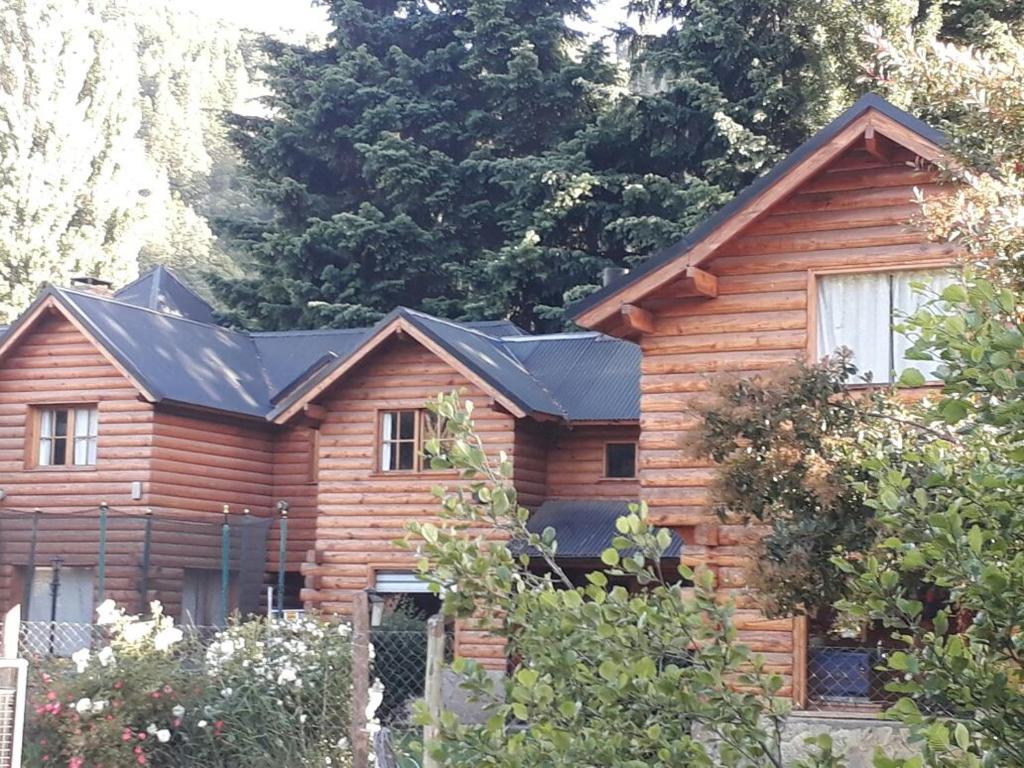 una casa de troncos con techo negro en dormi junto al arroyo, en San Martín de los Andes
