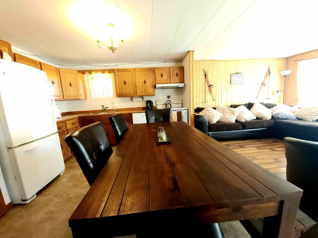 a living room with a wooden table and a kitchen at Maison au Pied du Mont Video in Barraute