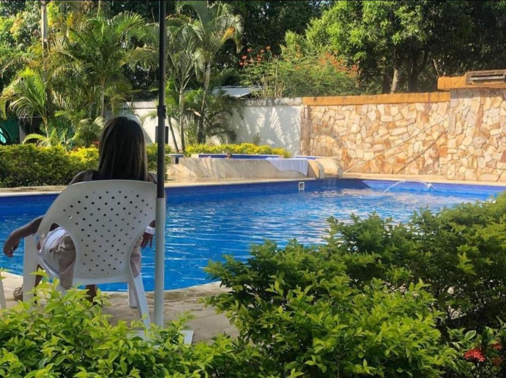 a woman sitting in a chair next to a swimming pool at Finca Villa Mary in Villavicencio