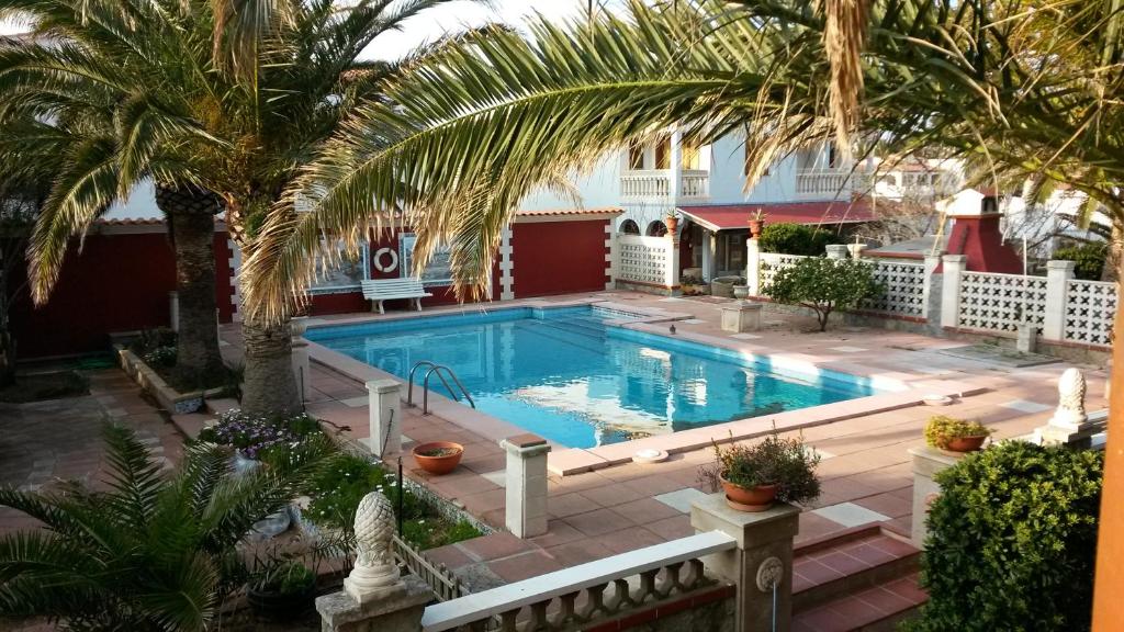 una piscina en un patio con palmeras en Las Belisas - Apartamentos en Arenal d'en Castell