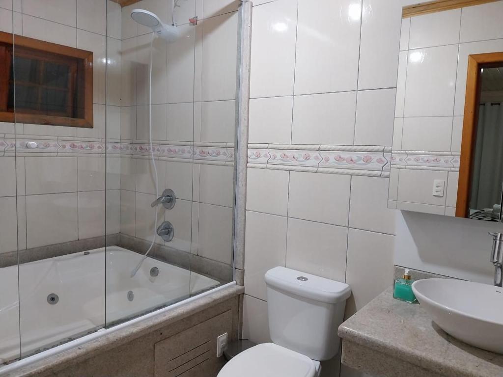 a bathroom with a toilet and a tub and a sink at Super Casa de 3 Quartos ao Lado da Igreja Matriz in Urubici