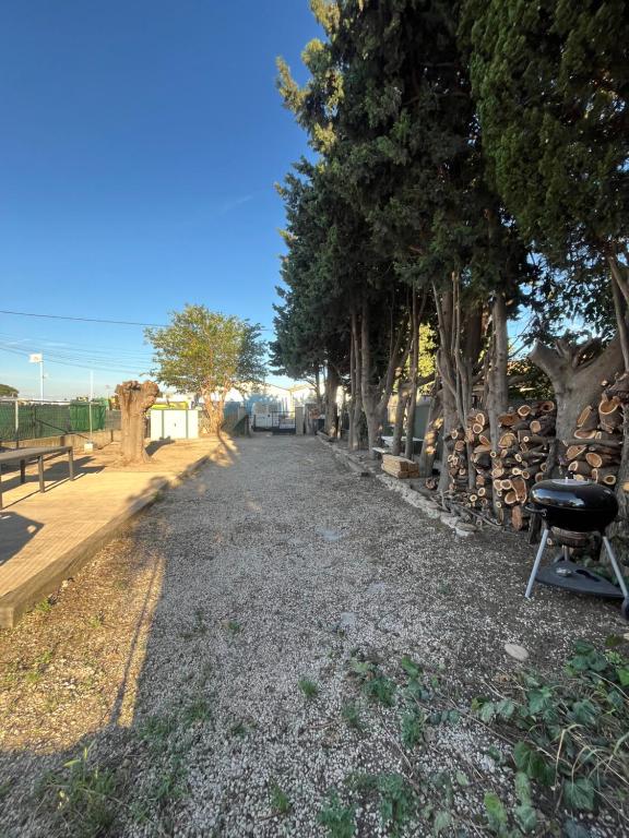 une route de gravier avec des arbres et un gril dessus dans l'établissement Haut de Villa, Jardin, Piscine !, à Fos-sur-Mer