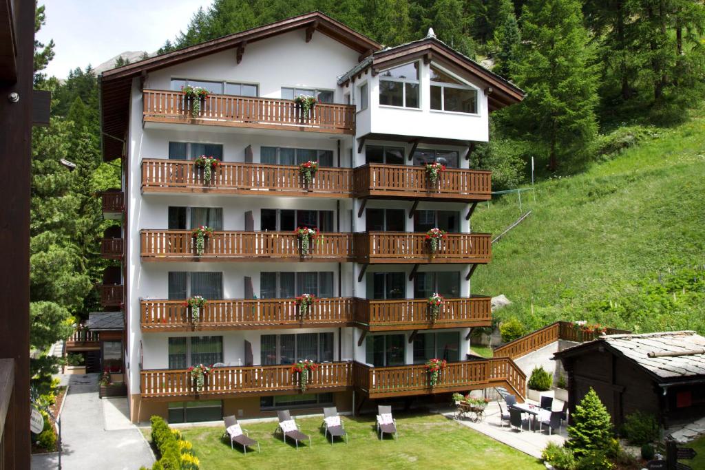 een gebouw met balkons, tafels en stoelen bij Jolimont Apartments in Zermatt