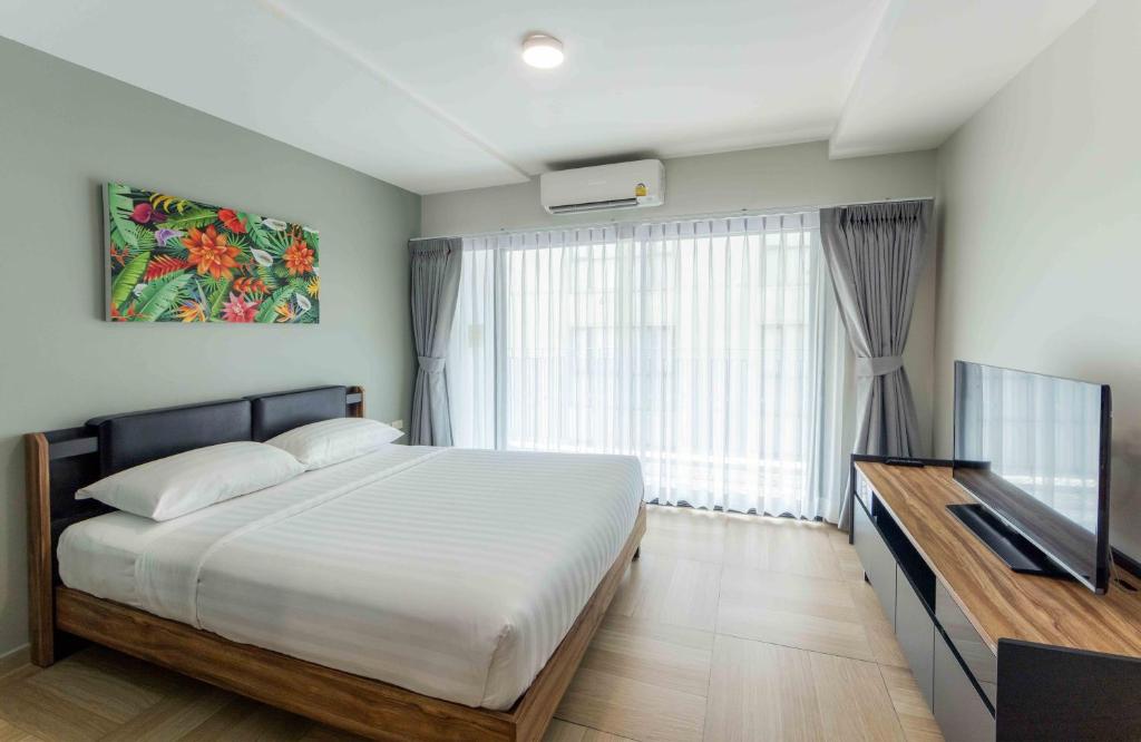 Un dormitorio con una cama y una ventana grande. en Chiva Bangkok Hotel - SHA Plus, en Bangkok