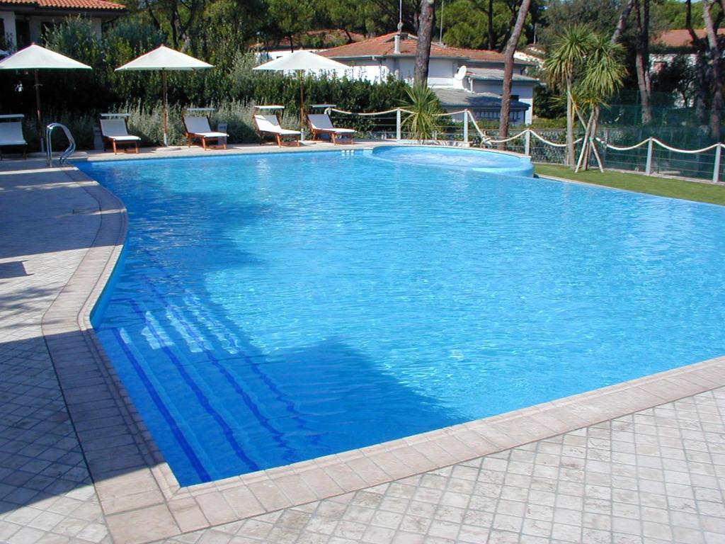a large blue swimming pool with chairs and umbrellas at Hotel Bristol in Tirrenia