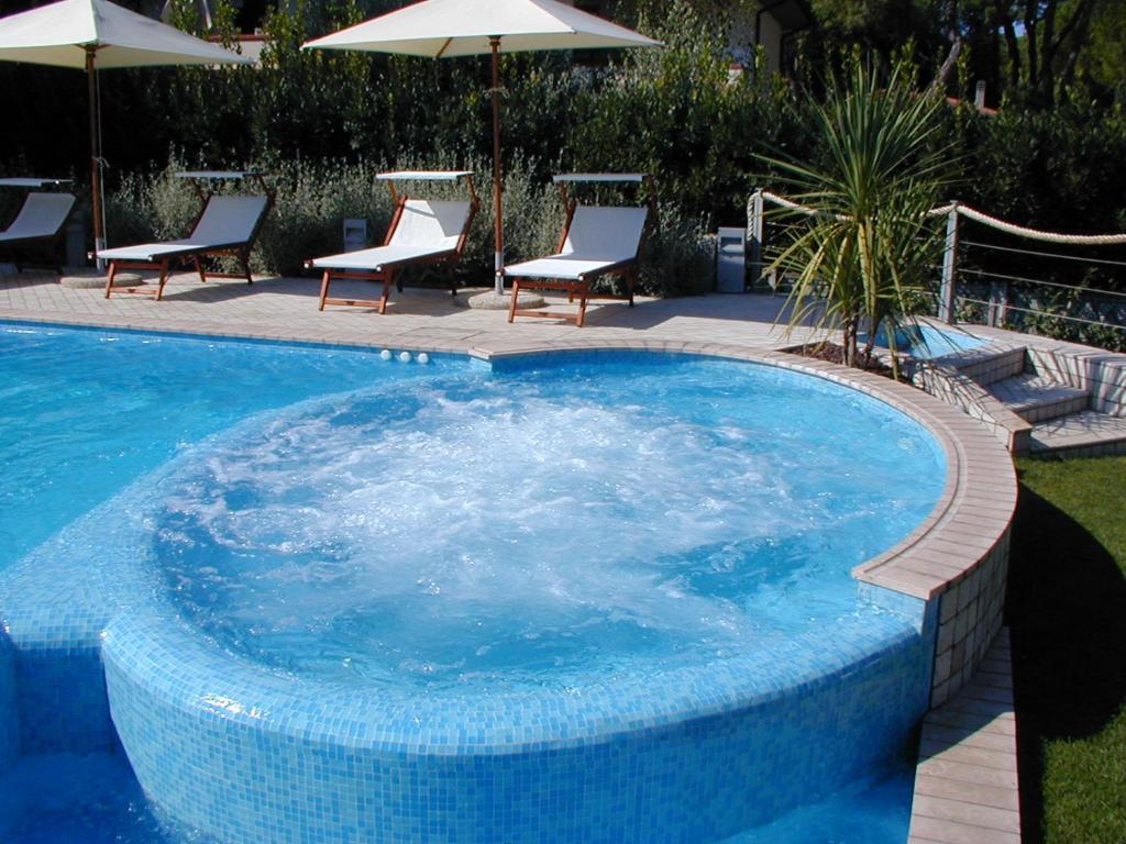 a large blue swimming pool with chairs and umbrellas at Hotel Bristol in Tirrenia