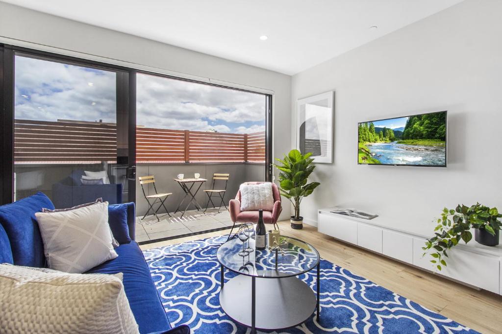 a living room with a blue couch and a glass table at Boutique apartment in quiet, sought-after suburb in Carnegie