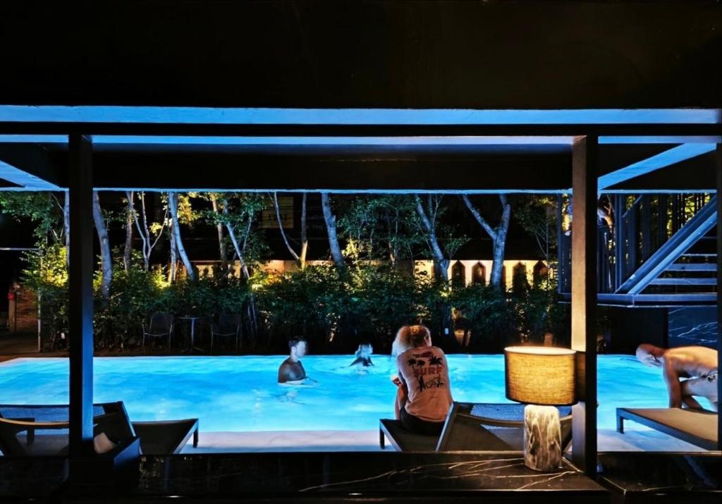 The illuminated pool at night, viewed from a covered seating area.