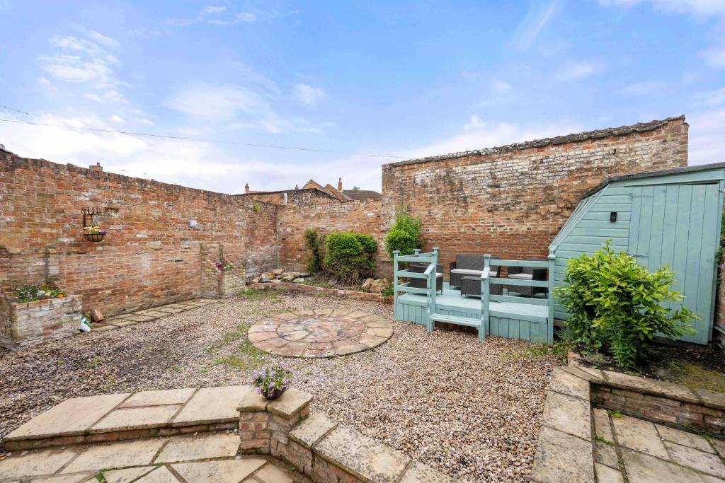 Un jardín con un cobertizo azul y una pared de ladrillos. en Monument House Horncastle, en Lincolnshire