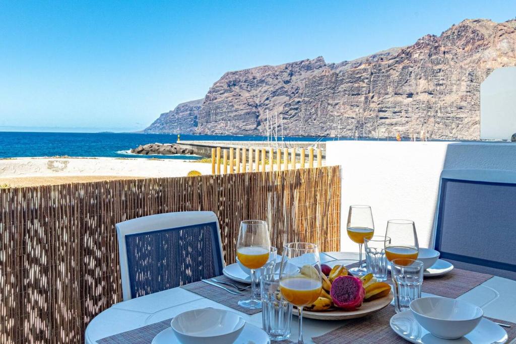 a table with glasses of wine and a view of the ocean at Oceanfront Oasis By Dream Homes Tenerife in Acantilado de los Gigantes