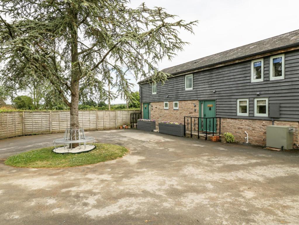 a tree in the middle of a driveway in front of a building at Bluebell Cottage in Leominster